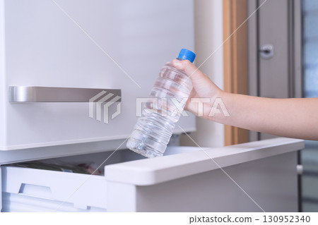 A child taking out a bottle of water from the refrigerator A child taking out a bottle of water from the refrigerator 130952340