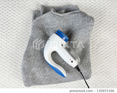 A lint remover against a warm cozy sweater with bobbles. Preparing wardrobe and caring for clothes, clothing care and maintenance, fall and winter fashion and garment preparation 130953166