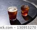 Two glasses of coffee iced americano and cold brew on a black table outside, showcasing rich colors and textures, with sunlight casting soft shadows, creating a refreshing beverage scene 130953270