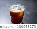 Refreshing iced coffee americano in a clear glass with ice cubes, placed on a dark surface, showcasing the rich color and texture of the beverage, perfect for summer enjoyment 130953273