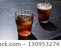 Two glasses of coffee iced americano and cold brew with ice cubes on a dark surface, showcasing rich colors and textures, perfect for summer refreshment and beverage enjoyment 130953274