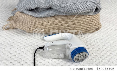 A lint remover against a warm cozy sweater with bobbles. Preparing wardrobe and caring for clothes, clothing care and maintenance, fall and winter fashion and garment preparation 130953396