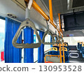 A row of orange hand straps hanging from the ceiling inside a public train or bus. The focus is on the nearest strap, the interior of the vehicle. The image highlights public transportation 130953528