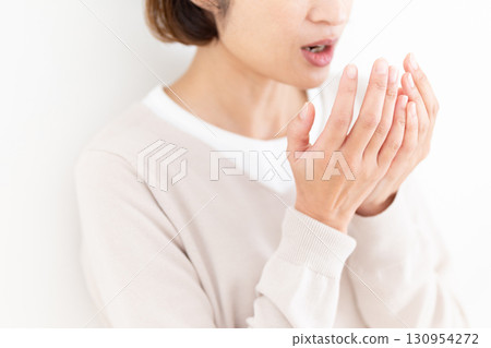 Middle-aged woman checking her bad breath Middle-aged woman checking her bad breath 130954272