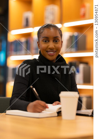 Focused student writing in library 130954871