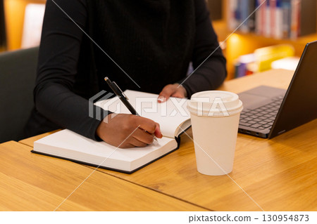 Woman writing in notebook with coffee Woman writing in notebook with coffee 130954873