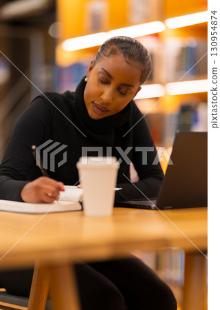 Focused student writing in library 130954874