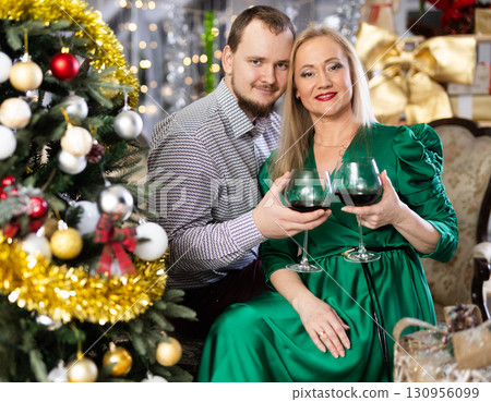 Husband and wife with glasses of red wine celebrate Christmas Husband and wife with glasses of red wine celebrate Christmas 130956099