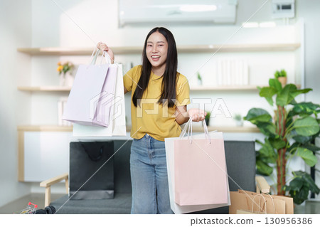 Shopping Happiness. Woman holding shopping bags after successful online purchases. 130956386