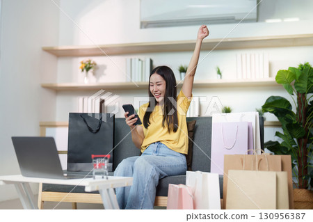 Celebrating Online Shopping Success. Woman cheering with phone after purchase. Celebrating Online Shopping Success. Woman cheering with phone after purchase. 130956387
