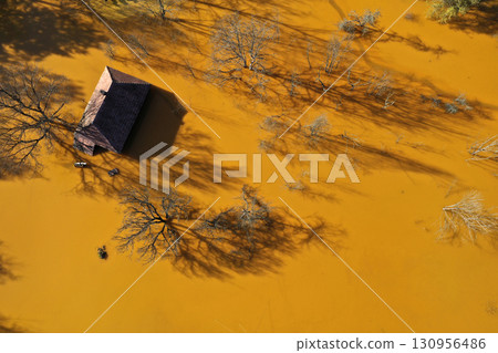 Aerial view of sinking village house in the middle of toxic mine decanting lake 130956486