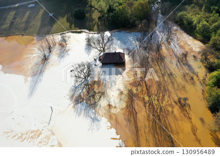 Aerial view of sinking village house in the middle of toxic mine decanting lake 130956489