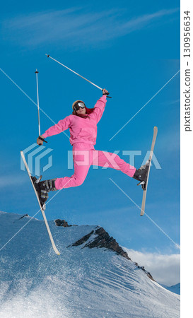Skier in pink suit performing aerial split jump with joyful energy over snowy mountain. Hand made collage 130956634
