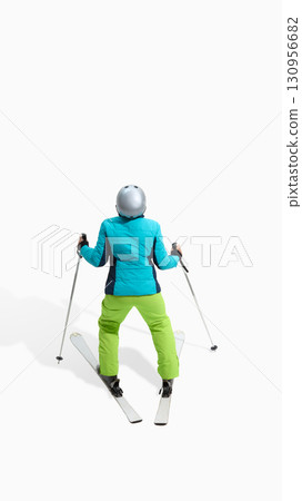 Female skier seen from back standing in relaxed position with ski poles isolated on white 130956682