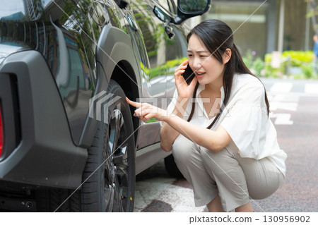女人用智慧型手機檢查汽車輪胎 130956902