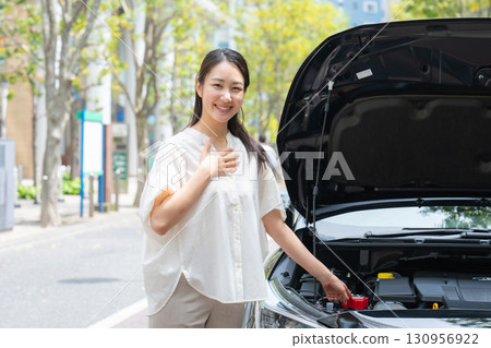A woman inspecting a car - Leave it to us A woman inspecting a car - Leave it to us 130956922