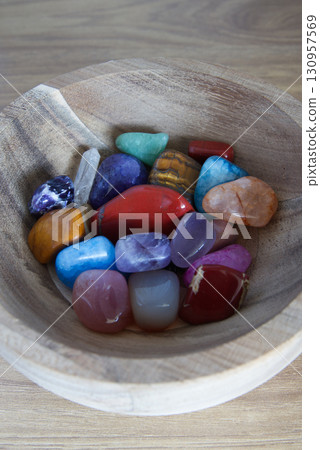 Different precious gem stones inside a wooden bowl 130957569