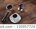 a cup of coffee, a coffee horn and a tamper on a wooden background close-up,  selective focus 130957728