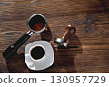 a cup of coffee, a coffee horn and a tamper on a wooden background close-up, copy space 130957729