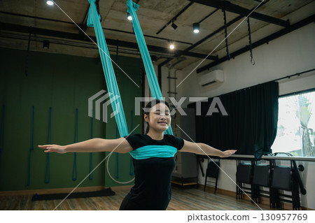 Teenage asian girl doing aerial yoga exercise for balance and relaxation. 130957769