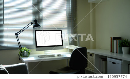 Bright workspace with desktop computer, office chair, and potted plant by the window 130957774