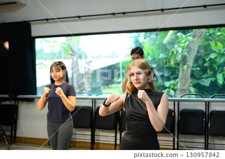 Fitness instructor leading boxing workout with students following punching exercises 130957842