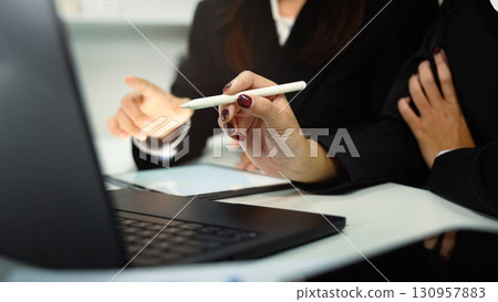 Close up of businesswomen collaborating on project using digital tablet at desk Close up of businesswomen collaborating on project using digital tablet at desk 130957883