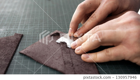 Leatherworker skiving edge of brown leather piece with blade tool Leatherworker skiving edge of brown leather piece with blade tool 130957946