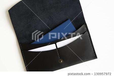 Black leather envelope with blue notebook and white paper isolated on clean white background Black leather envelope with blue notebook and white paper isolated on clean white background 130957972