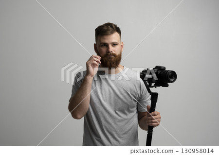 Bearded man holding professional camera on stabilizer for filmmaking and video work 130958014
