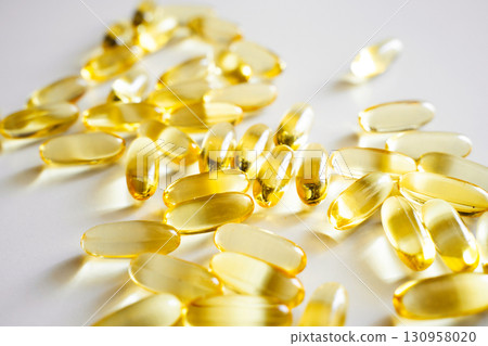 Yellow omega fish oil capsules close up on white background for health and wellness Yellow omega fish oil capsules close up on white background for health and wellness 130958020