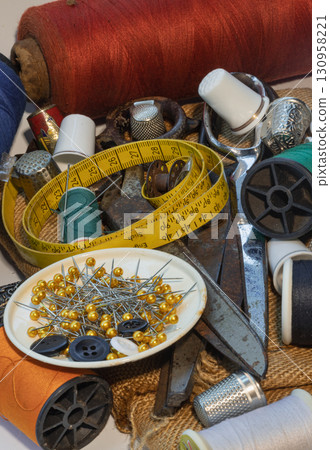 Sewing needles stuck in a green miniature spools thread Steel scissors, Spools of thread of various colour, Thimbles and Measuring tape including Pins and Buttons in small round tray. 130958221