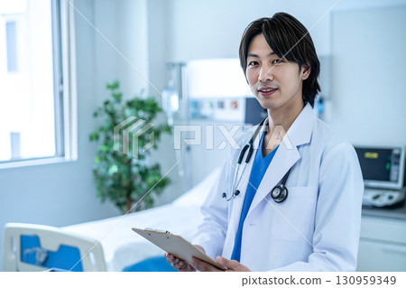 Friendly male doctor holding a clipboard in a hospital room 130959349