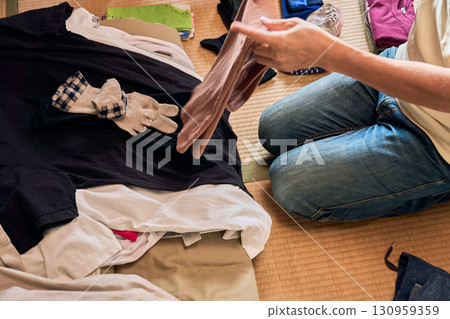 A series of photographs of a man sitting on a tatami mat and folding laundry. A man doing housework. A series of photographs of a man sitting on a tatami mat and folding laundry. A man doing housework. 130959359