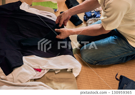 A series of photographs of a man sitting on a tatami mat and folding laundry. A man doing housework. A series of photographs of a man sitting on a tatami mat and folding laundry. A man doing housework. 130959365