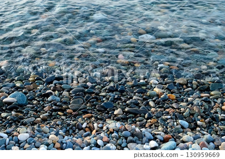 Stone pebble beach with small pebbles and calm sea transparent water surface. Stone pebble beach with small pebbles and calm sea transparent water surface. 130959669