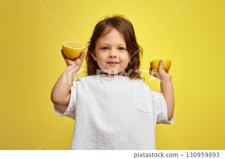 cute funny little child girl holding lemon on yellow background cute funny little child girl holding lemon on yellow background 130959893