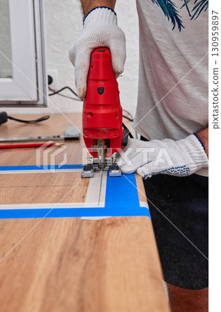 repairman using electric handheld jigsaw and cutting hole for the sink in the kitchen countertops, Woodworking and carpentry concept 130959897