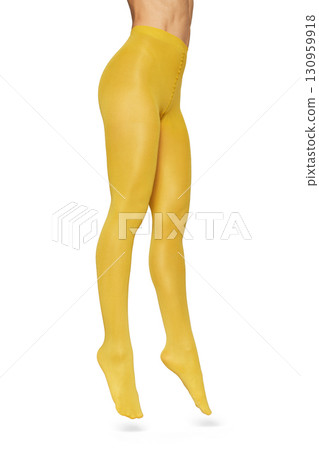 Beautiful long fit female legs in yellow tights jumping on white background 130959918