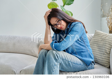 Sad upset young woman sitting on sofa at home Sad upset young woman sitting on sofa at home 130960106