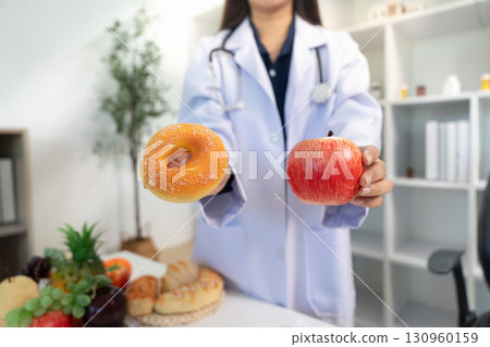 Healthy Choices: Doctor Presenting Apple and Donut to Patient Healthy Choices: Doctor Presenting Apple and Donut to Patient 130960159