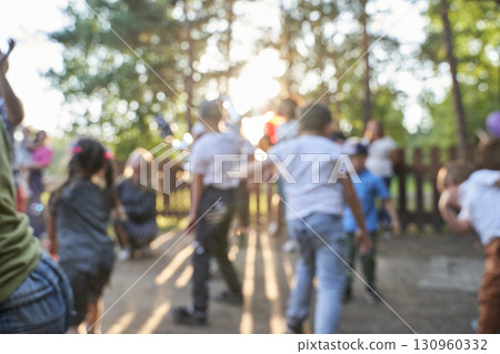 Blurry image of diverse group of children playing outdoors in sunlit park 130960332