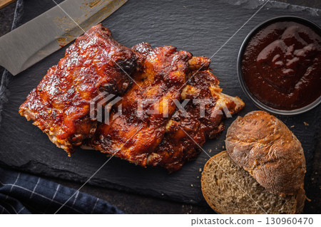 Pork BBQ glazed ribs and sauce on black table. Top view. Pork BBQ glazed ribs and sauce on black table. Top view. 130960470