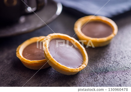 Sweet chocolate tartelettes on black table. 130960478