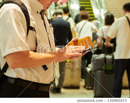 一名中年男子上班族在上下班途中，在車站檢票口與其他人一起看智慧型手機 130960815