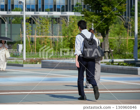 A male office worker on his way to work crosses the west plaza of Kanazawa Station on a summer morning 130960846