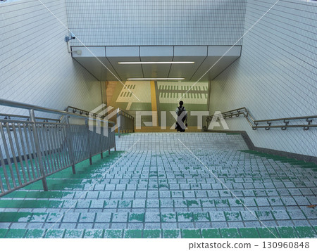 A female office worker on her way to work descends the stairs in the underground plaza of the station A female office worker on her way to work descends the stairs in the underground plaza of the station 130960848