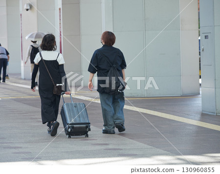 A female tourist with a suitcase crossing the Hospitality Dome Square east of Kanazawa Station on a summer morning 130960855