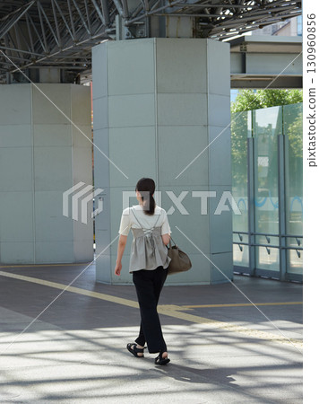 A young female office worker crossing the hospitality dome plaza east of Kanazawa Station on a summer morning 130960856