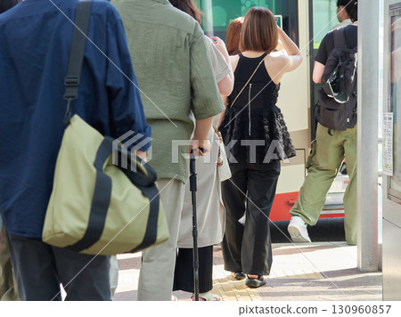Male and female passengers at a bus stop in the city on a summer morning 130960857